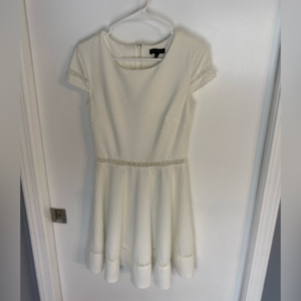 A super cute white dress with lacy cutout at waist, bottom, and sleeves.